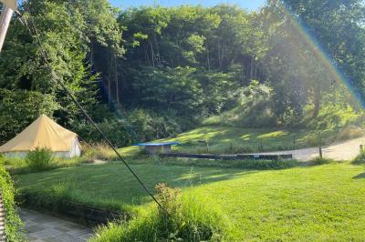 Intérieur d'une tente avec matelas, coffre noir, tapis coloré et vue partielle sur un paysage extérieur.