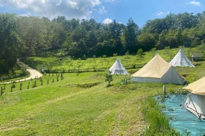 Intérieur d'une tente avec matelas, coffre noir, tapis coloré et vue partielle sur un paysage extérieur.