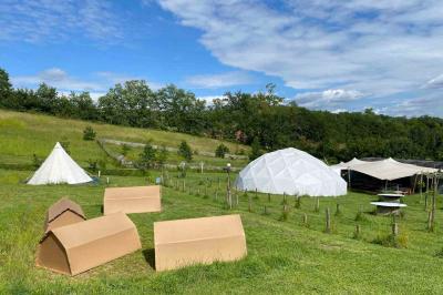Intérieur d'une tente avec matelas, coffre noir, tapis coloré et vue partielle sur un paysage extérieur.