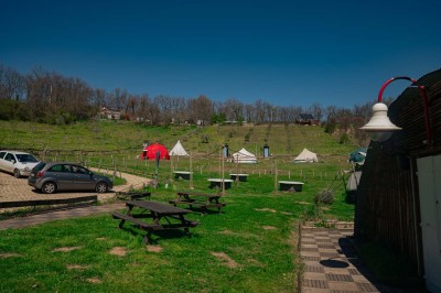 Intérieur d'une tente avec matelas, coffre noir, tapis coloré et vue partielle sur un paysage extérieur.