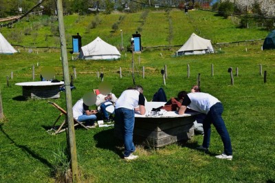 Intérieur d'une tente avec matelas, coffre noir, tapis coloré et vue partielle sur un paysage extérieur.