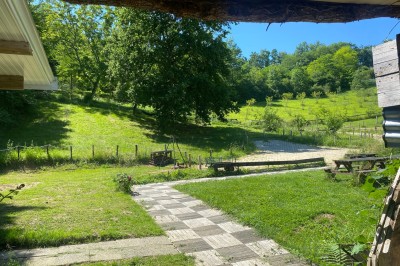 Salle commune avec tables, chaises, télévision murale, meubles en bois et sol carrelé, éclairée par des plafonniers.
