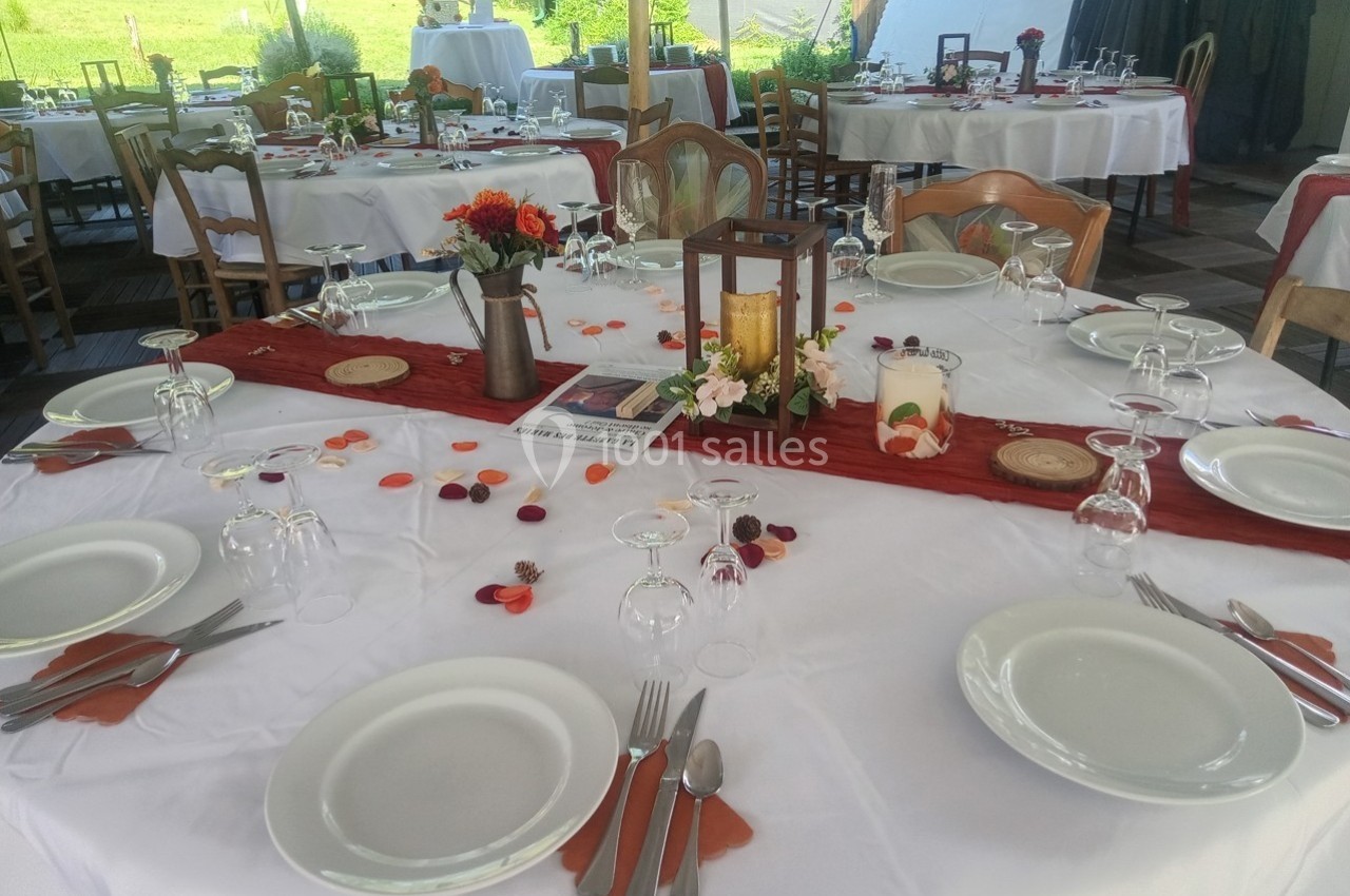 Table dressée pour un repas festif, avec nappes blanches, décorations florales et lanternes au centre.
