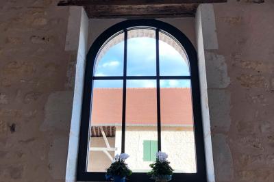Chambre lumineuse avec un lit double, murs en pierre et peinture bleue, parquet en bois et fenêtre donnant sur la campagne.