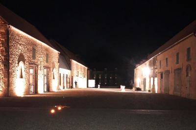 Chambre lumineuse avec un lit double, murs en pierre et peinture bleue, parquet en bois et fenêtre donnant sur la campagne.