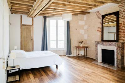 Chambre lumineuse avec un lit double, murs en pierre et peinture bleue, parquet en bois et fenêtre donnant sur la campagne.