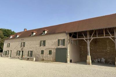 Chambre lumineuse avec un lit double, murs en pierre et peinture bleue, parquet en bois et fenêtre donnant sur la campagne.