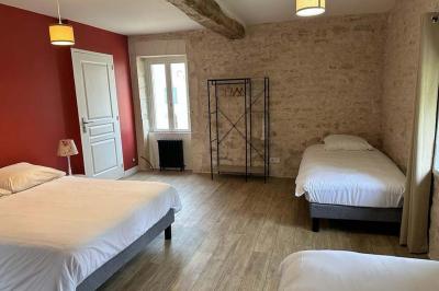 Chambre lumineuse avec un lit double, murs en pierre et peinture bleue, parquet en bois et fenêtre donnant sur la campagne.