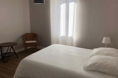 Chambre lumineuse avec un lit double, murs en pierre et peinture bleue, parquet en bois et fenêtre donnant sur la campagne.