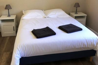 Chambre lumineuse avec un lit double, murs en pierre et peinture bleue, parquet en bois et fenêtre donnant sur la campagne.