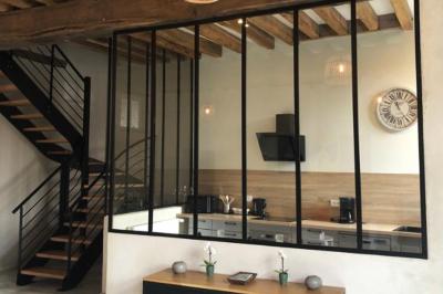 Chambre lumineuse avec un lit double, murs en pierre et peinture bleue, parquet en bois et fenêtre donnant sur la campagne.