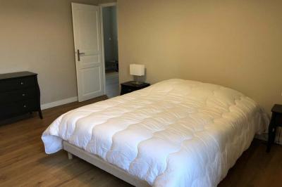 Chambre lumineuse avec un lit double, murs en pierre et peinture bleue, parquet en bois et fenêtre donnant sur la campagne.