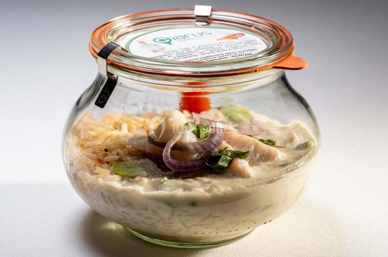 Bocal en verre contenant un plat crémeux avec morceaux de poisson, rondelles d'oignon rouge et herbes fraîches.