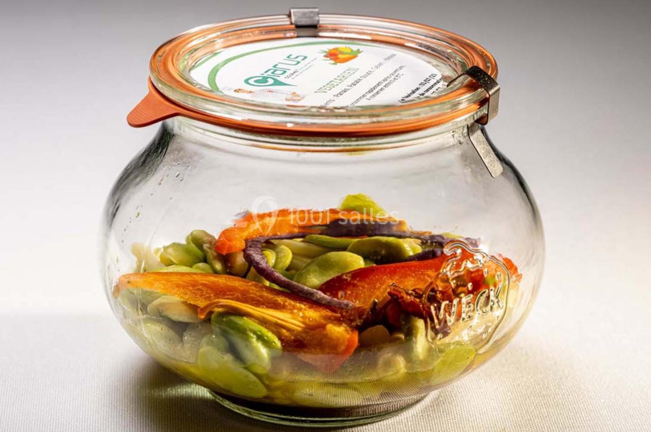 Bocal en verre contenant des légumes colorés, notamment des fèves, des carottes et des oignons, avec un couvercle hermétique.