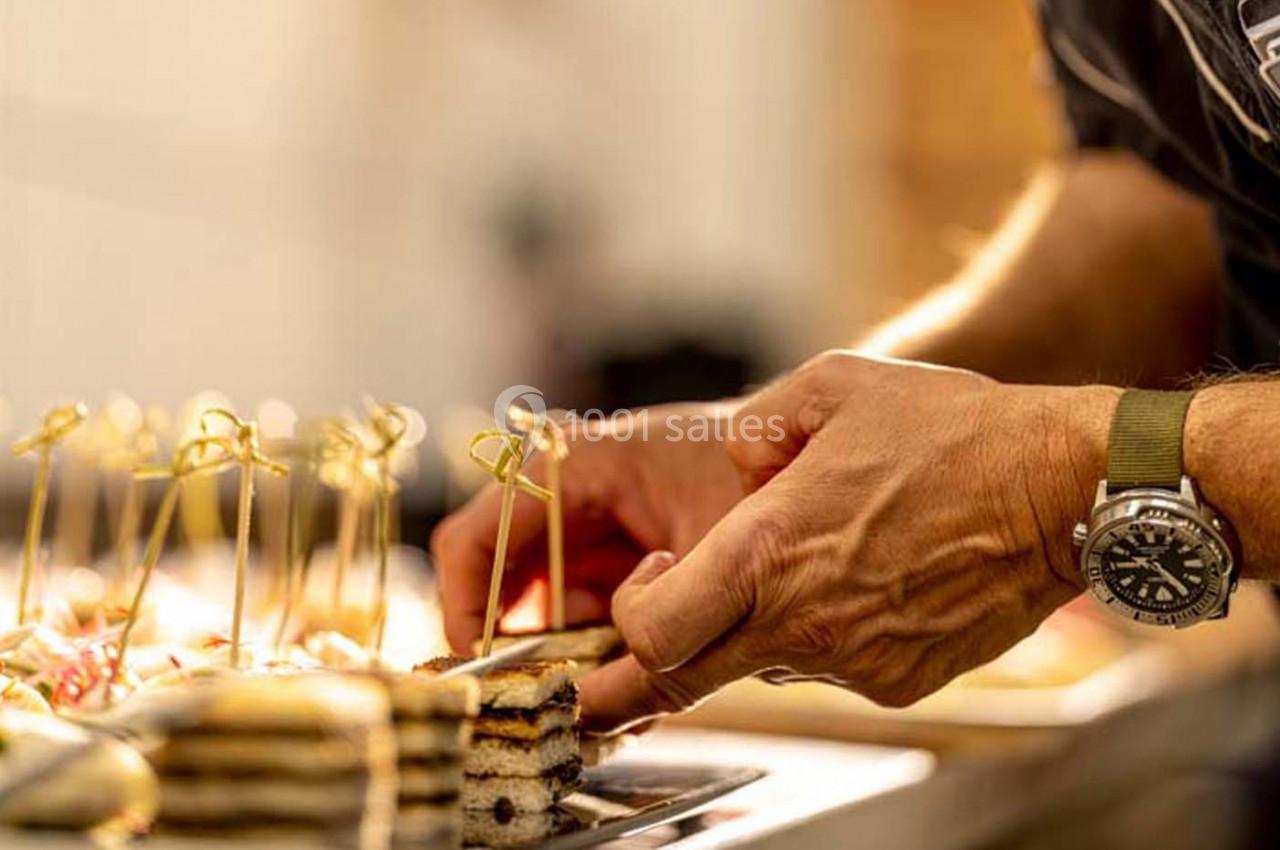 Un chef dispose soigneusement des amuse-bouches garnis de brochettes dorées sur un plateau.