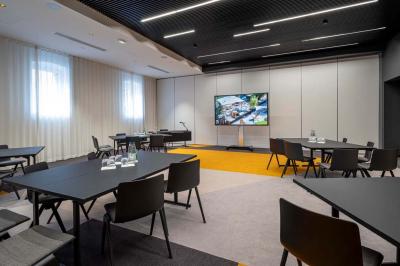 Chambre lumineuse avec un lit simple, des lits superposés en bois, un bureau et une fenêtre donnant sur des toits.