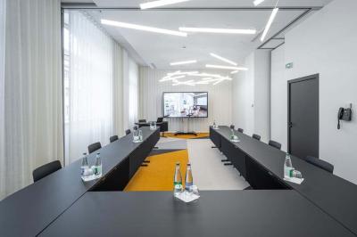 Chambre lumineuse avec un lit simple, des lits superposés en bois, un bureau et une fenêtre donnant sur des toits.