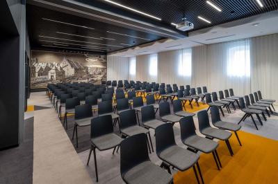 Chambre lumineuse avec un lit simple, des lits superposés en bois, un bureau et une fenêtre donnant sur des toits.