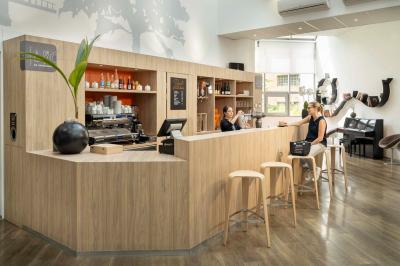 Chambre lumineuse avec un lit simple, des lits superposés en bois, un bureau et une fenêtre donnant sur des toits.