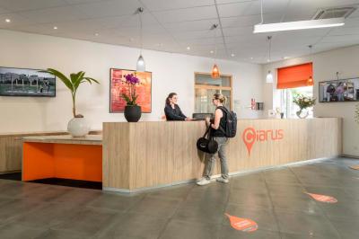 Chambre lumineuse avec un lit simple, des lits superposés en bois, un bureau et une fenêtre donnant sur des toits.