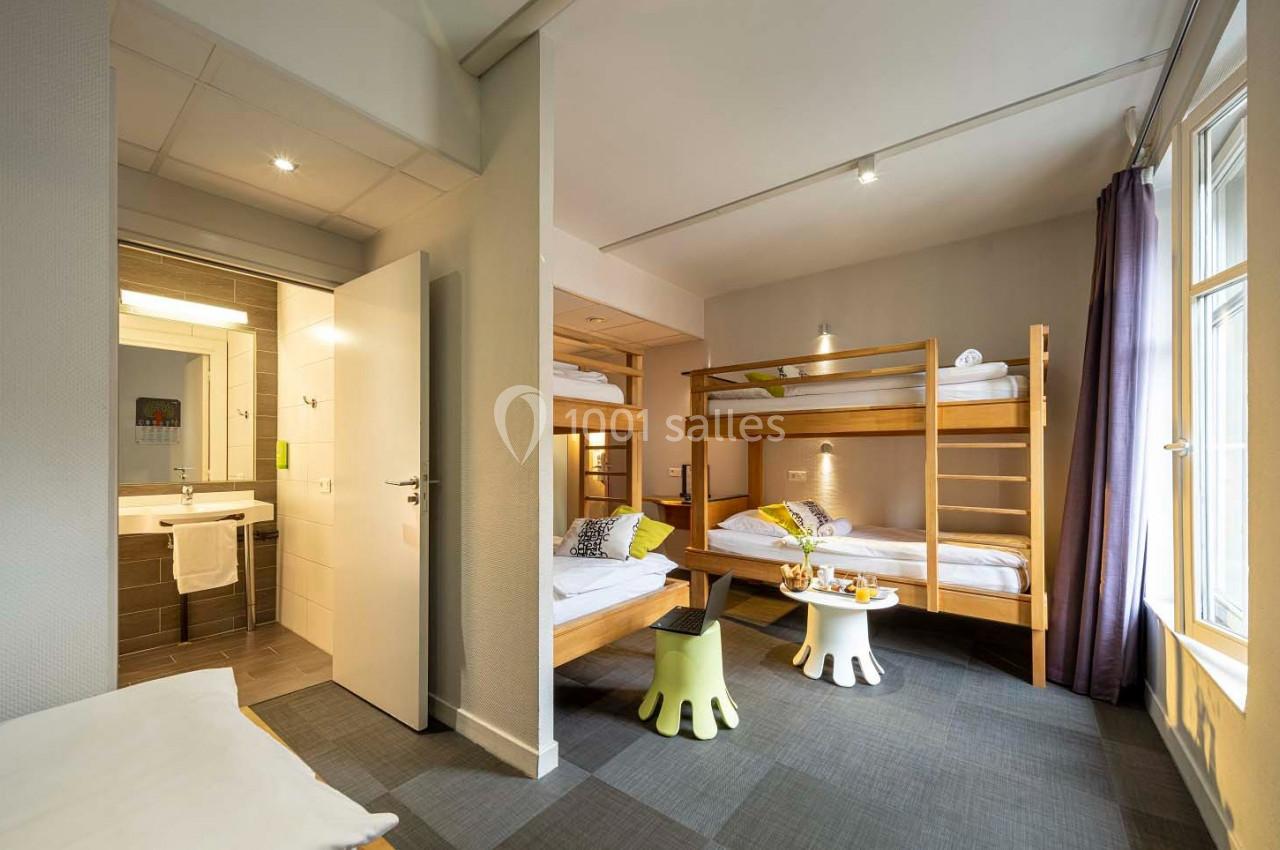 Chambre lumineuse avec lits superposés en bois, salle de bain attenante et grande fenêtre laissant entrer la lumière…