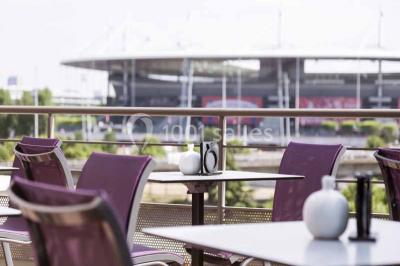 Façade d'un hôtel Novotel moderne éclairé en soirée, avec des lampadaires allumés au premier plan.