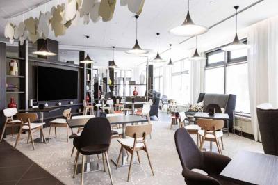 Façade d'un hôtel Novotel moderne éclairé en soirée, avec des lampadaires allumés au premier plan.