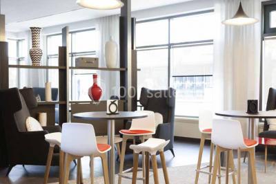 Façade d'un hôtel Novotel moderne éclairé en soirée, avec des lampadaires allumés au premier plan.