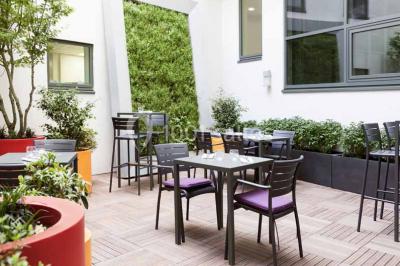 Façade d'un hôtel Novotel moderne éclairé en soirée, avec des lampadaires allumés au premier plan.