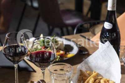 Assiette de repas avec légumes colorés, gratin, pain et verres de vin rouge sur une table en bois.