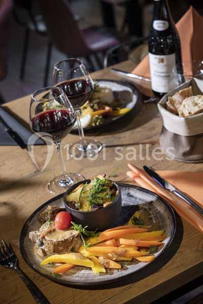 Assiette de repas avec légumes colorés, gratin, pain et verres de vin rouge sur une table en bois.