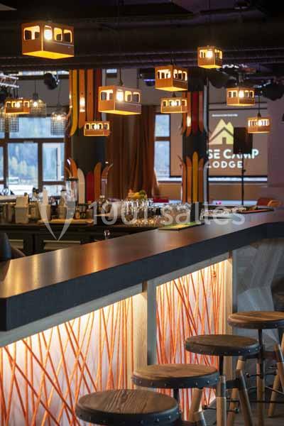 Bar moderne avec comptoir éclairé, tabourets en bois et suspensions lumineuses dans un espace chaleureux.