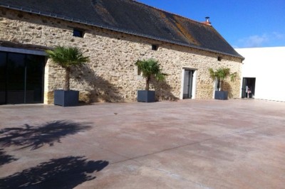 Deux lavabos blancs encastrés dans un plan de travail sombre, avec miroirs et distributeurs de savon muraux rouges.