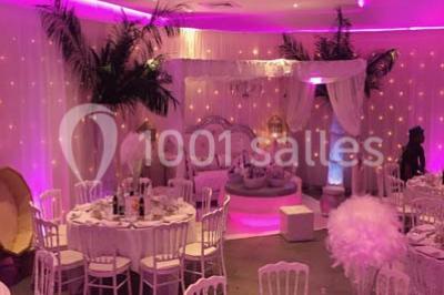 Scène de DJ éclairée par des lumières colorées, entourée de rideaux rouges et de haut-parleurs dans une salle.