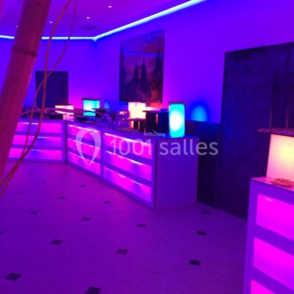 Salle éclairée par des lumières LED violettes et bleues, avec un buffet lumineux aligné contre un mur.