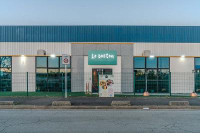 Salle intérieure avec terrain de sport entouré de filets, tables et chaises disposées sur un sol en gazon synthétique.
