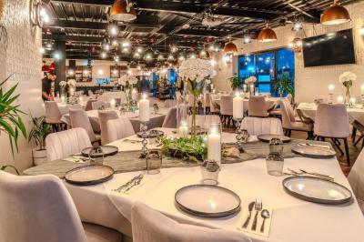 Salle intérieure avec terrain de sport entouré de filets, tables et chaises disposées sur un sol en gazon synthétique.