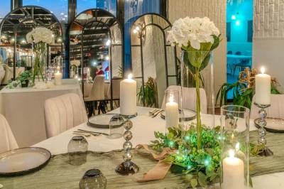 Salle intérieure avec terrain de sport entouré de filets, tables et chaises disposées sur un sol en gazon synthétique.