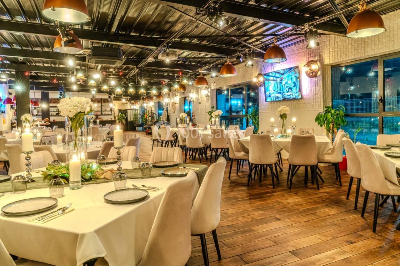 Salle de restaurant élégante avec tables dressées, éclairage chaleureux et décoration moderne.