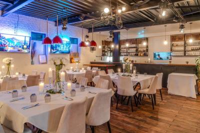 Salle intérieure avec terrain de sport entouré de filets, tables et chaises disposées sur un sol en gazon synthétique.