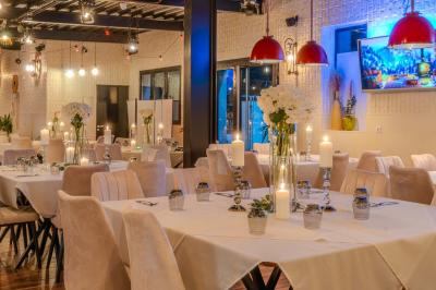 Salle intérieure avec terrain de sport entouré de filets, tables et chaises disposées sur un sol en gazon synthétique.