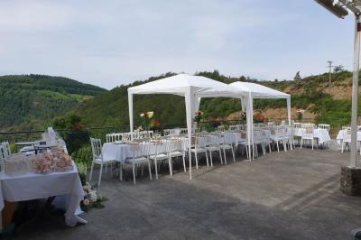 Tables dressées pour un repas en extérieur devant une maison en pierre et crépi, avec une borne photo à gauche.