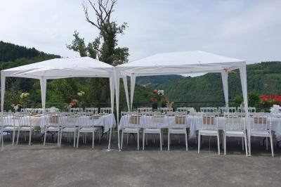 Tables dressées pour un repas en extérieur devant une maison en pierre et crépi, avec une borne photo à gauche.