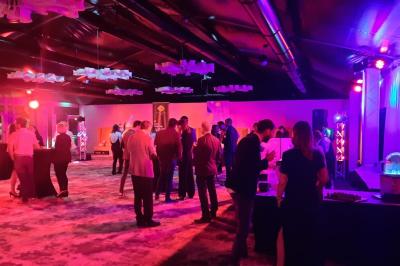 Un public assis dans une salle de conférence, attentif à une présentation sur une scène éclairée.