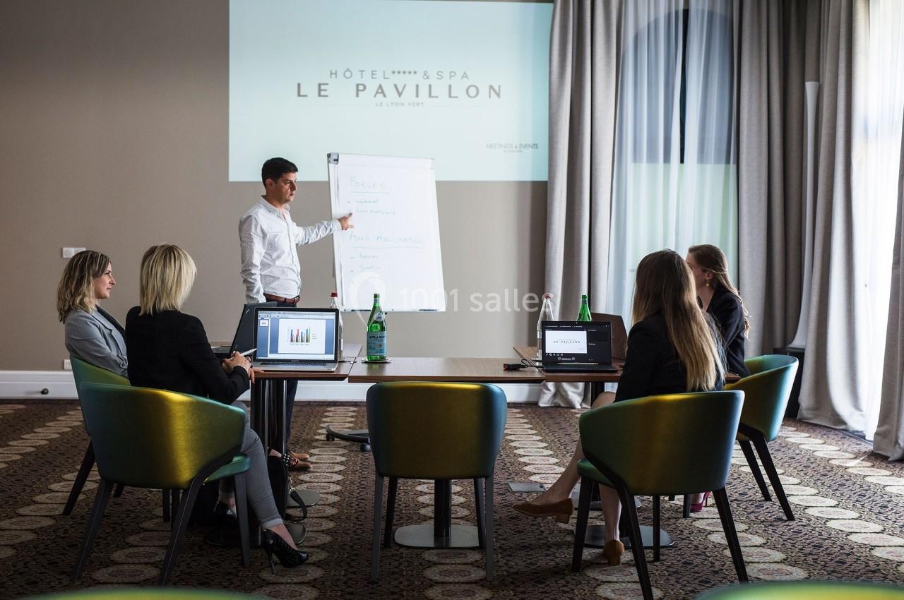 Un homme présente des informations sur un tableau blanc à un groupe de personnes dans une salle de réunion d'hôtel.