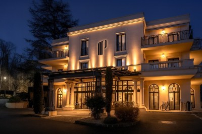 Des invités dînent autour de tables rondes tandis qu'un groupe joue sur une scène illuminée dans une salle de réception.
