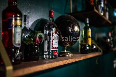 Comptoir de bar sombre avec des bougies allumées, décoré de motifs floraux et éclairé par une lumière tamisée.