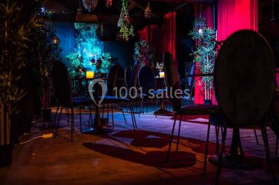 Comptoir de bar sombre avec des bougies allumées, décoré de motifs floraux et éclairé par une lumière tamisée.