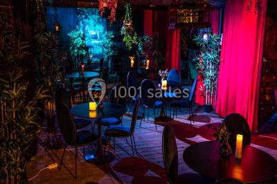 Comptoir de bar sombre avec des bougies allumées, décoré de motifs floraux et éclairé par une lumière tamisée.