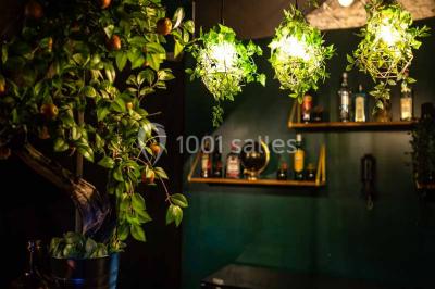 Bar décoré de plantes, bougies et éclairage tamisé, avec un robinet de bière en métal sur le comptoir.